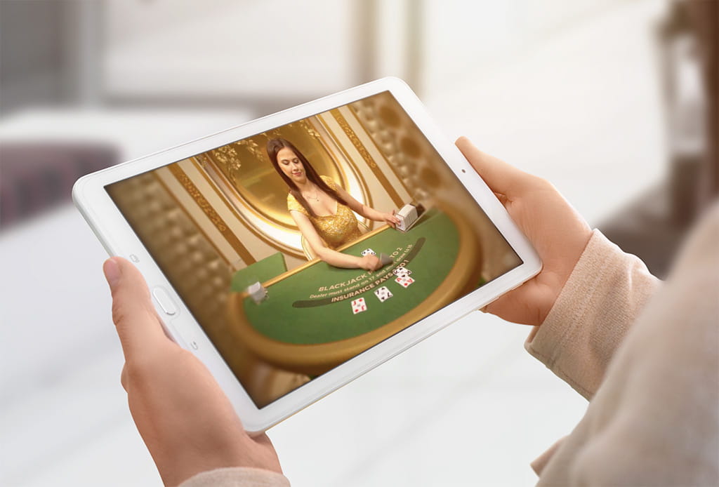 Ein Tablet mit einem Blackjack Spiel wird in Händen gehalten.
